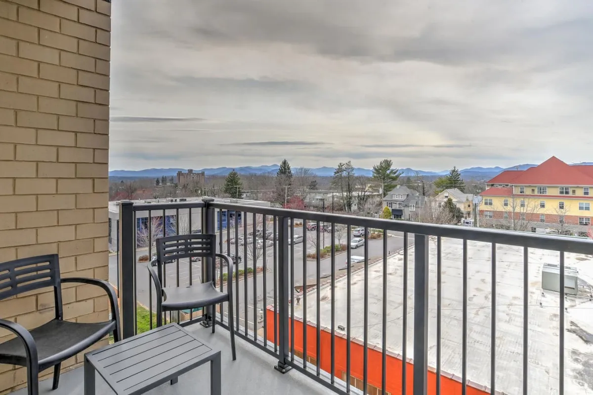An exterior shot of the private balcony with a railing overlooking a sweeping mountain and urban landscape. The balcony is staged for relaxation, with hints of sunrise and sunset ambiance, capturing the tranquil and inspiring views promised by the section.